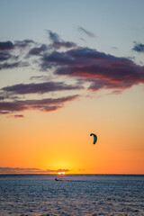 Man kitesurfing at sunset during a beautiful orange sunset on the lagoon of La Saline les Bains in...