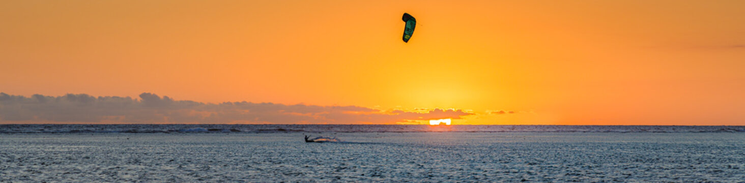 Man kitesurfing at sunset during a beautiful orange sunset on the lagoon of La Saline les Bains in Saint-Gilles on Reunion Island