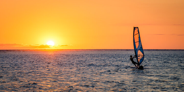 Man windsurfing at sunset on Reunion Island - Powered by Adobe