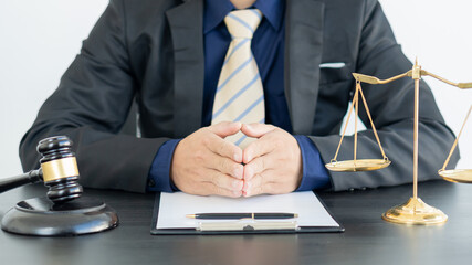 The lawyer puts his hands on the table and the hammer and scales of Uncle Justice in the office.