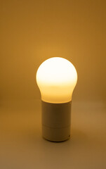 illuminated warm light electric light bulb opened on yellow background