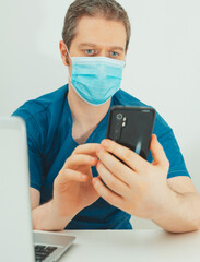 Medical doctor in protective mask having video conference with patient.