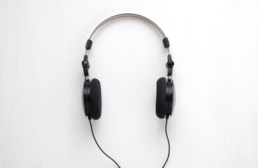 Wired headphones for listening to music on a white wooden back. Concept to illustrate listening to music.