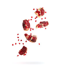 pieces of pomegranate falling, grains and pomegranate slices flying down isolated on white background