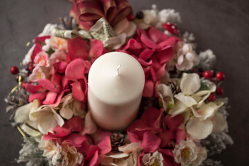Top view closeup of a Christmas white candle with ribbons and branches on a grey background