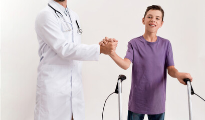 Cropped shot of male doctor shaking hands with teenaged disabled boy with cerebral palsy, taking...