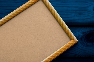 Empty beige wooden frame with antique paper on the dark blue surface of the wooden slats. Copy space, top view. Christmas theme.