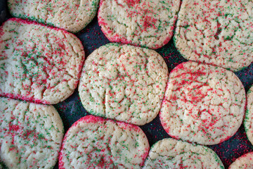 baking sheet of baked sugar cookies with red and green sprinkles flat lay