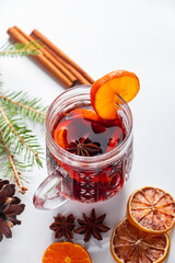 Winter warming mulled wine in glass cup on white background.