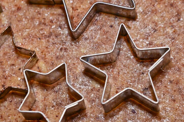 cookie cutters in form of stars and a dough roller flat lay on rolled out pastry for Christmas