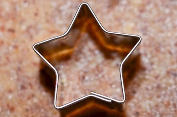 cookie cutters in form of stars and a dough roller flat lay on rolled out pastry for Christmas