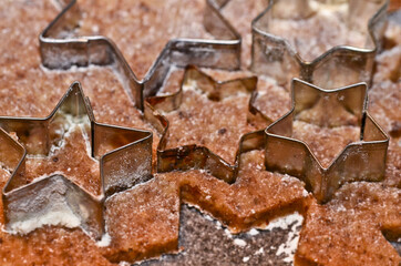 cookie cutters in form of stars and a dough roller flat lay on rolled out pastry for Christmas