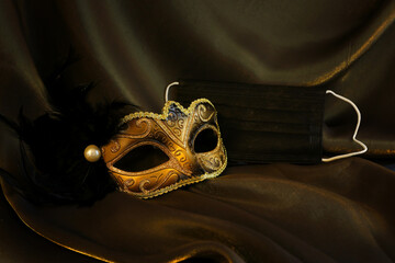 Photo of elegant and delicate gold Venetian mask over black silk background. Coronavirus prevention...