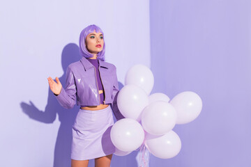 Fototapeta premium young woman dressed in doll style with balloons on violet colorful background