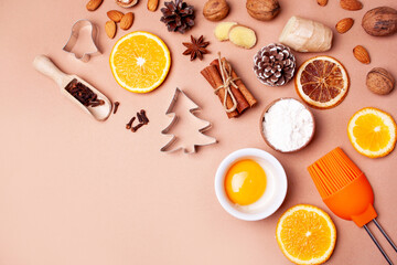 Cooking gingerbread Christmas cookies on a peach background. Ingredients. Flat lay style. Cinnamon, nuts, oranges