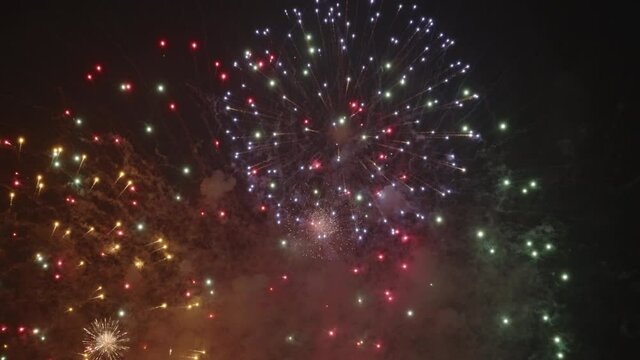 Bursting Colorful Fireworks Illuminated Through Calm Evening Sky - Celebration - Low Angle Shot, Slow Motion