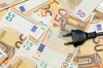 Electric cable with plug on banknotes. Expensive energy and cost of electricity concept.