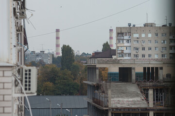 Autumn city landscape. White high-rise building and chimneys of a thermal power plant against a gray sky