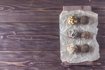 Raw vegan healthy energy balls with oatmeal, chia seed, coconut flakes, cocoa, sesame, almond and dried fruits on dark wooden background. Top view. Place for text.