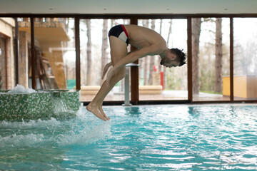 Young man jumping in swimming pool