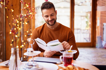 Relaxed man reading a book in the cafe