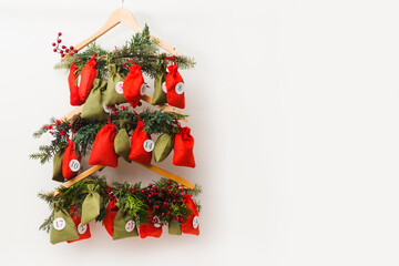 Christmas Advent Calendar hanging with gifts on white wall. copy space
