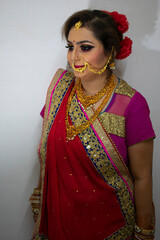 a beautiful Indian girl in bridal dress wearing red saree and gold ornaments