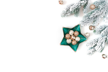 Christmas composition. Snow-covered fir branches, golden balls in a green plate in the shape of a star are on a white background. New Year card. Flat lay, top view, copy space.