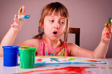 The process of painting, art, learning to draw concept. Young beauutiful girl with hands painted in...