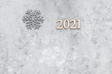 Happy 2021 New Year. Snowflake and wooden numbers on a gray concrete grunge background. Minimal New Year's composition.