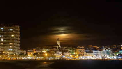 Fototapeta na wymiar Night shot with full moon behind the clouds,town Palamos in Spanish Costa Brava , Catalonia