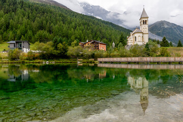 Fototapeta na wymiar The parish church of Solda, South Tyrol, Italy, is reflected in the water of the lake