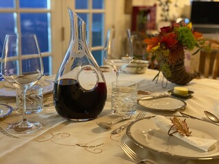 Holiday dinner table with a decanter of red wine and festive decorations
