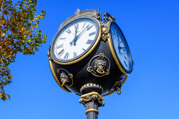 Fototapeta na wymiar Vintage style black and grey metallic clock towards clear blue sky in Unirii Park (Parcul Unirii), in Bucharest, Romania, in a sunny autumn day.