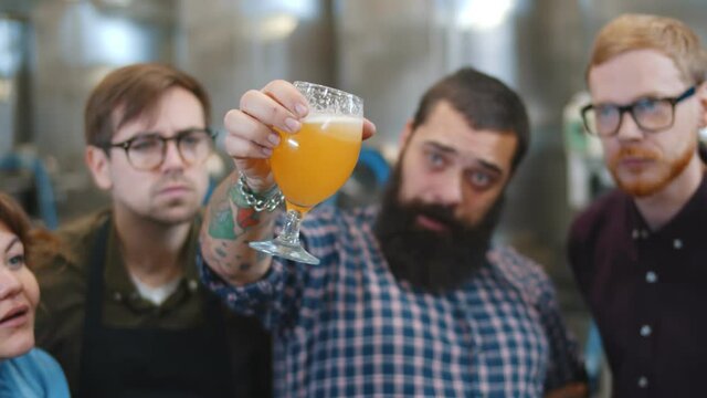 Specialist standing with glasses of beer explaining brewing process to visitors
