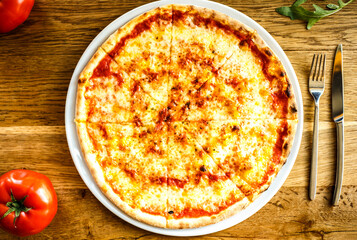 Cripsy pizza Margherita served on a wooden table in trattoria italiana