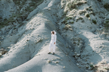 Man wearing a beekeeper dress in a dry apocalyptical landscape