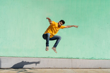 Casual man jumping in front of colorful wall