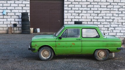 Old abandoned rusted light green colored soviet retro car near auto repair shop ready for tuning.Used second hand car.