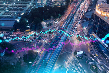 FOREX and stock market chart hologram on aerial view of road, busy urban traffic highway at night. Junction network of transportation infrastructure. The concept of international trading.
