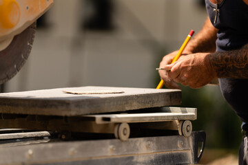 Handwerker markiert mit einem Stifft den Schnitt mit einer Kreissäge auf einer Betonplatte