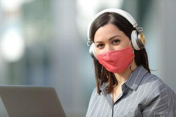 Woman with mask laptop and headphones looks at you