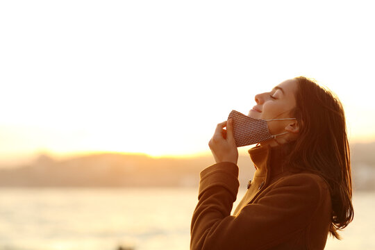 Woman taking off mask to breath fresh air on the beach