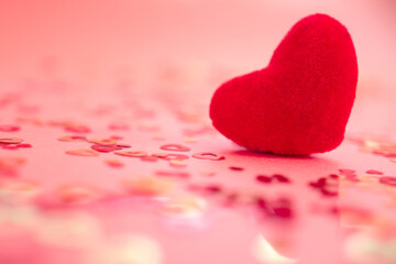 Red heart on a blurry background with confetti.