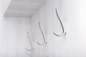 Wall empty hooks on white wooden board.