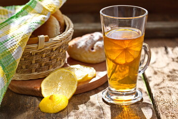 Chilled tea with lemon on a wooden table. Next on the kitchen breadboard with homemade cakes. Comfortably. House.Family.The concept of Good morning.