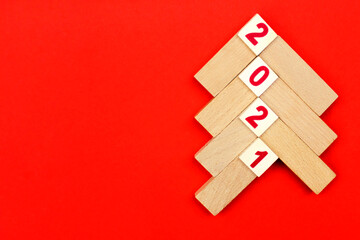 Christmas tree made of light wooden bars on a red background with the numbers 2021