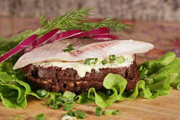 Sandwich with herring. Red onion, rye bread on a brown table.    Tradition Danish open sandwich smorrebrod with herring, egg, cucumber and onions. Dark bread sandwich.  