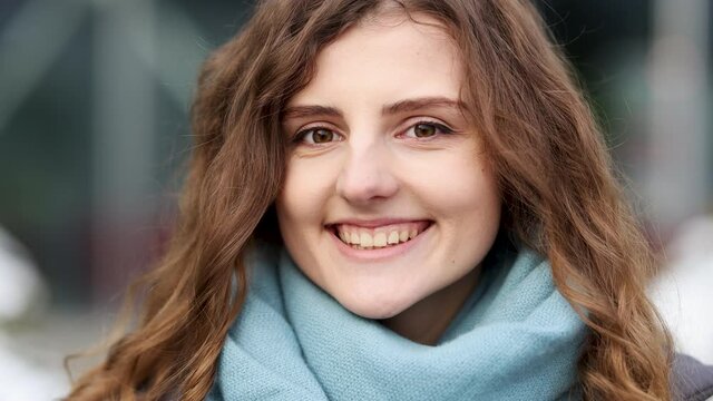 Portrait attractive curly woman winking eye and smiling into camera. Close up face playful young woman winking eye. Positive people emotions. Playful happy contented woman blinking eye