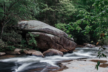 Naklejka na ściany i meble The mountain river flows among huge gray stones and trees with green foliage. Scenic highway 11 (eleven). Long Shoals Roadside State Park, SC, USA